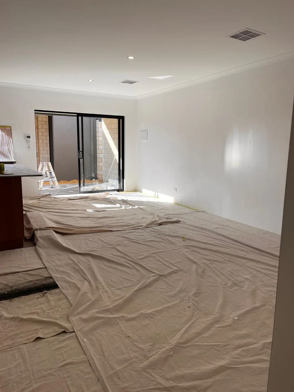 The open-plan living area with drop sheets down, walls finished to the slider