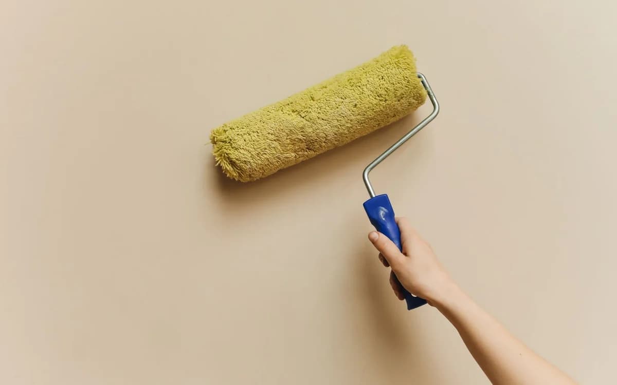 A roller applying paint to a plain interior wall