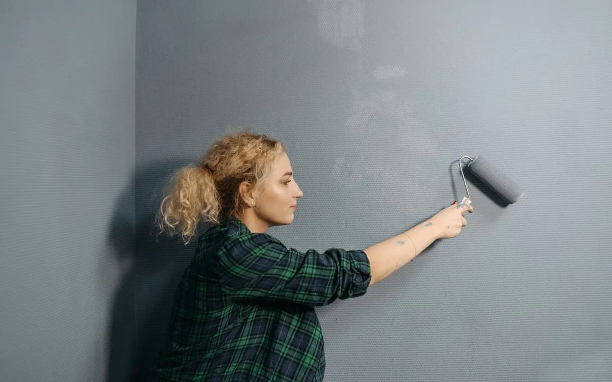 Grey paint being rolled onto an interior wall