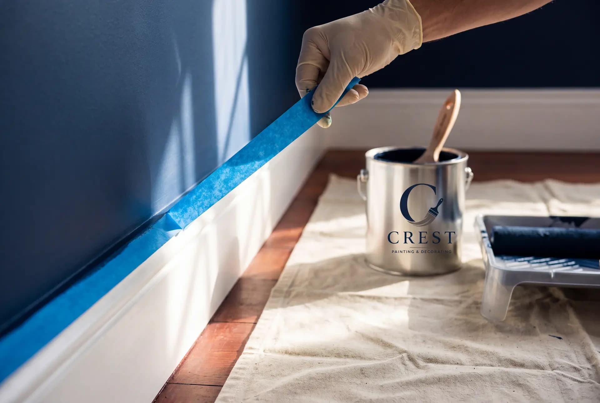 Masking tape pulled away at forty-five degrees revealing a razor-sharp line between a deep navy wall and a white skirting board