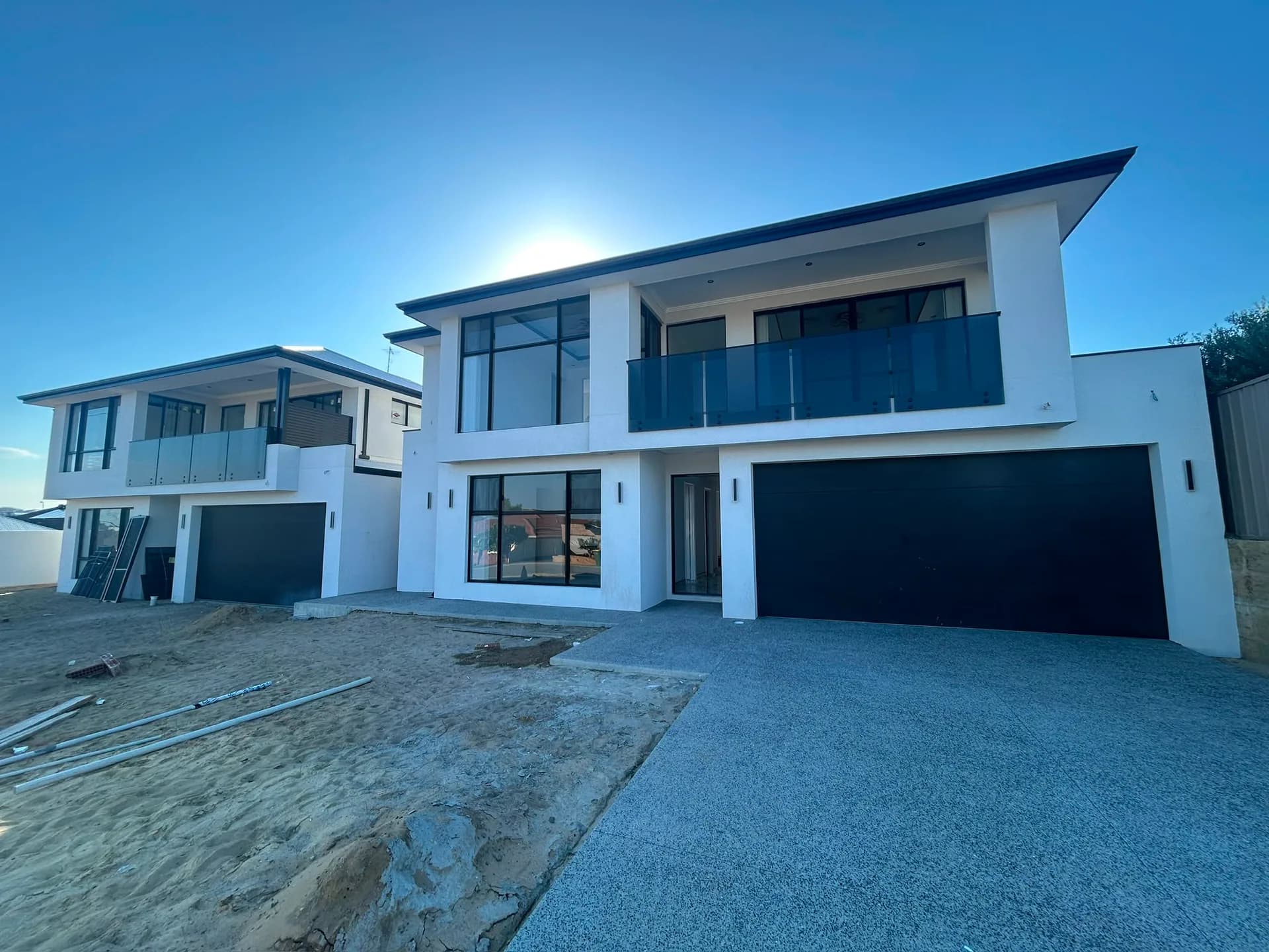 A two-storey Perth new build finished by CREST — white render, dark trim and a glass balustrade under a clear sky