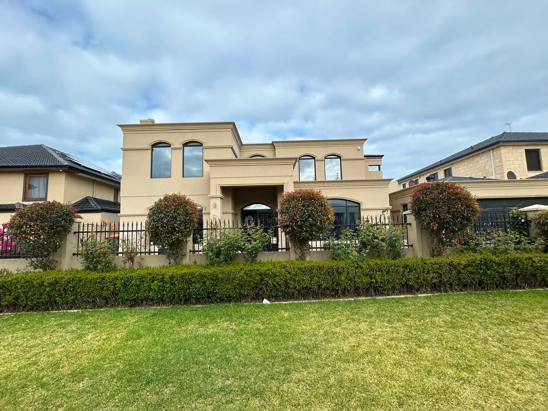 A large rendered Perth home repainted by CREST, hedged front garden in the foreground