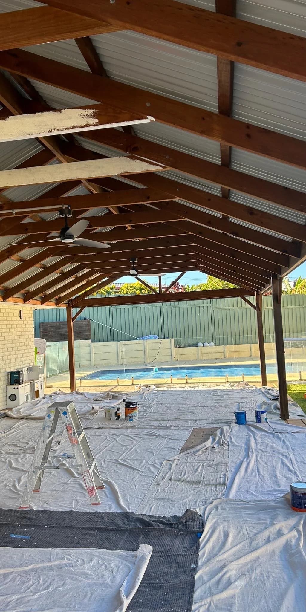 a timber pergola over a pool, before and after painting — before